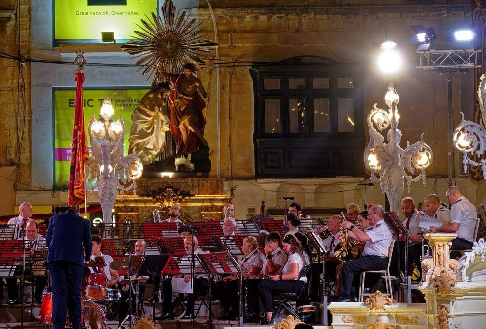 A village brass band playing in front of a processional statue