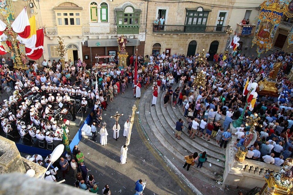 A statue procession on festa day, with a brass band and crowds in the street